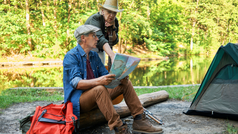Camping For Seniors - Man and Woman looking at map while hiking