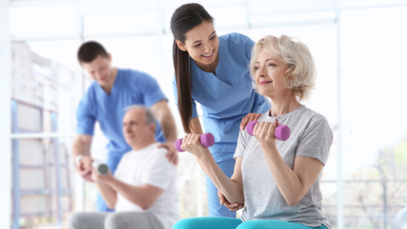 Physiotherapists teaching strength training to elderly man and woman