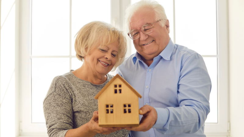 downsizing checklist for seniors - senior couple holding small replica of home