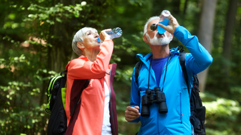 Hiking For Seniors - Man and woman hiking drinking water